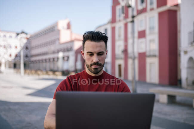 Hombre guapo usando portátil en la ciudad - foto de stock