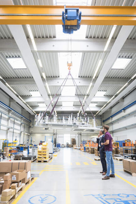 Deux hommes avec grue intérieure dans une usine — Photo de stock