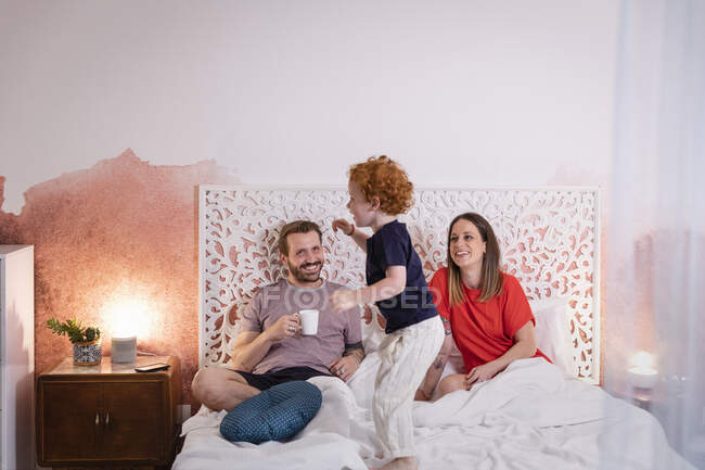 Genitori che guardano il figlio giocoso mentre si rilassano sul letto — Foto stock