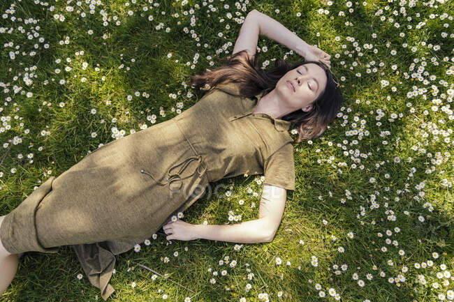 Жінка насолоджувалася вільним часом, лежачи на траві з маргаритками. — стокове фото