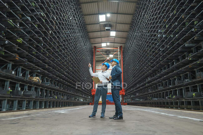 Zwei Geschäftsleute treffen sich in einem Hochregallager einer Fabrik — Stockfoto