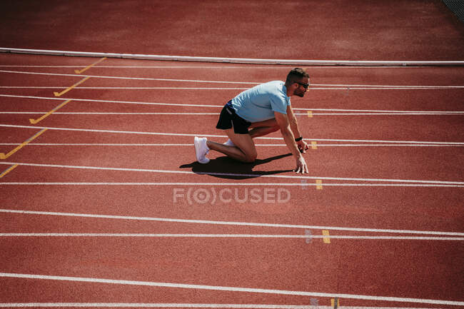 Männlicher Athlet in Startposition auf der Tartanbahn — Stockfoto