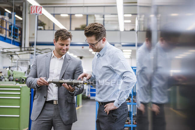 Dos empresarios examinan un producto en una fábrica - foto de stock