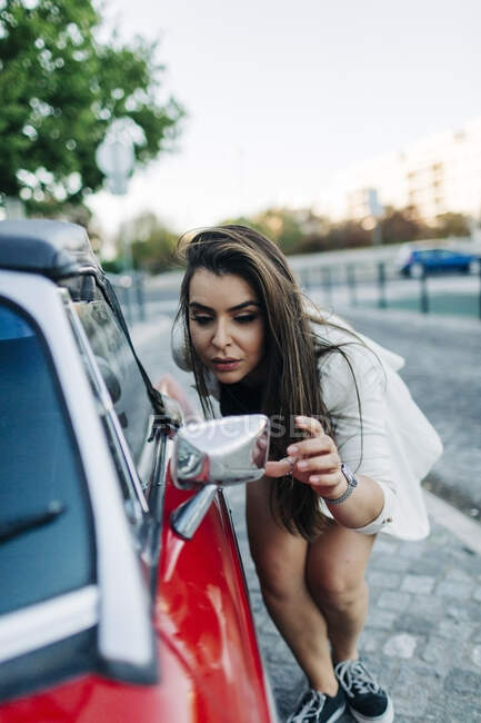 Jovem mulher verificando seu olhar no espelho do carro — Fotografia de Stock