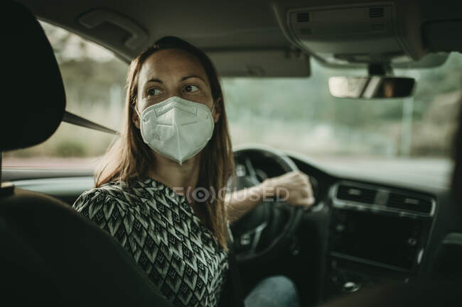 Metà donna adulta con maschera protettiva in auto — Foto stock