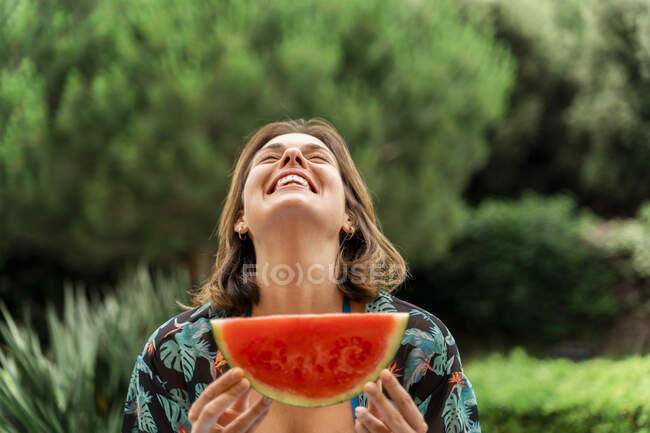 Giovane donna allegra con fetta di anguria in cortile — Foto stock