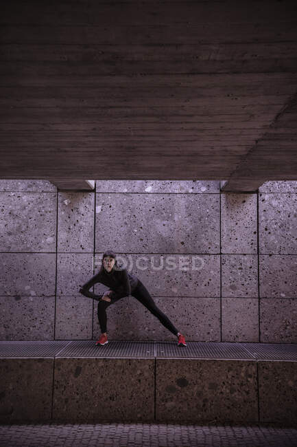 Female athlete warming up before running in pedestrian underpass — Stock Photo