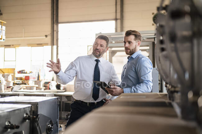 Два бизнесмена с планшетом встречаются на заводе — стоковое фото