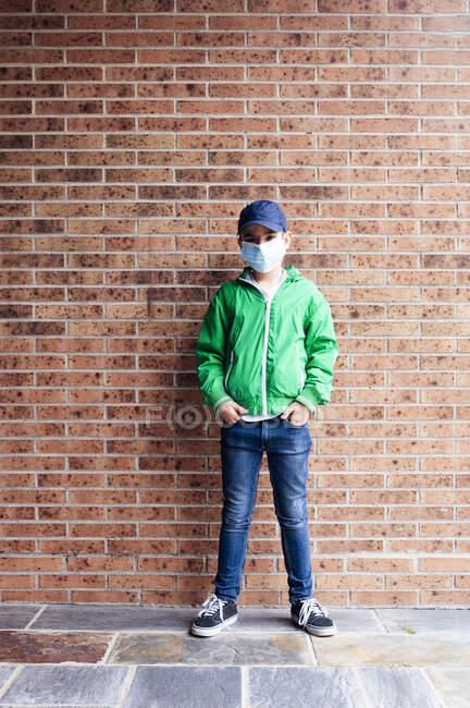 Мальчик в защитной маске стоит перед кирпичной стеной — стоковое фото
