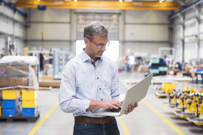 Зрелый мужчина с ноутбуком на заводе — стоковое фото