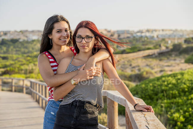 Affettuose ragazze adolescenti che si abbracciano sul lungomare in spiaggia contro il cielo limpido — Foto stock