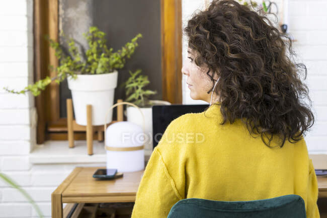 Вид сзади женщины, работающей за столом в домашнем офисе — стоковое фото
