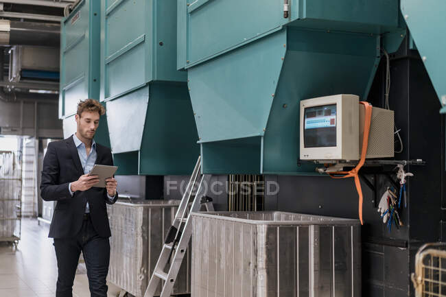 Joven hombre de negocios usando tableta en una fábrica - foto de stock
