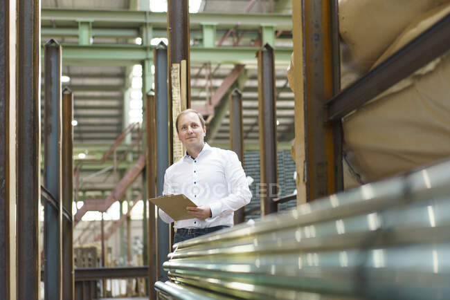 Homme d'affaires avec presse-papiers à tuyaux en acier dans une usine — Photo de stock