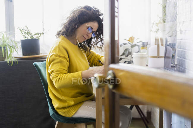 Женщина, работающая за столом в домашнем офисе — стоковое фото