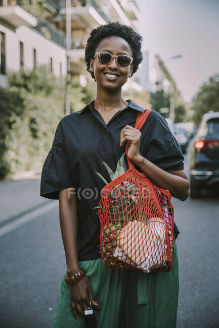 Ritratto di giovane donna sorridente in piedi sulla strada con il suo acquisto — Foto stock