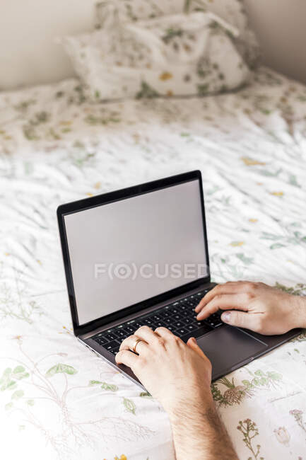 Man using laptop on bed — Stock Photo