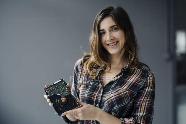 Ritratto di giovane donna sorridente che mostra il disco rigido — Foto stock