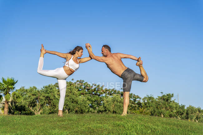 Coppia matura che fa yoga sul prato sotto il sole insieme — Foto stock