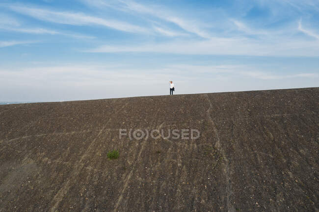 Hombre empresario de pie en la colina contra el cielo durante el día soleado - foto de stock