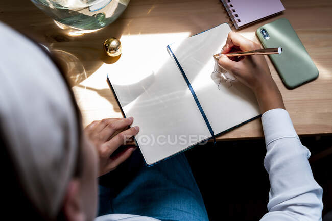 Mitte erwachsene Frau zeichnet Tagebuch auf Schreibtisch zu Hause — Stockfoto