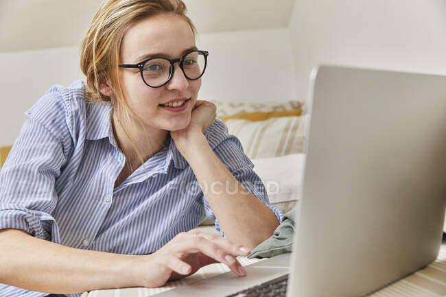 Porträt einer lächelnden jungen Frau mit Laptop zu Hause — Stockfoto
