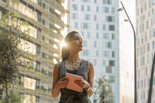 Appunti premuroso imprenditore femminile tenendo nota mentre in piedi contro gli edifici nella città moderna — Foto stock