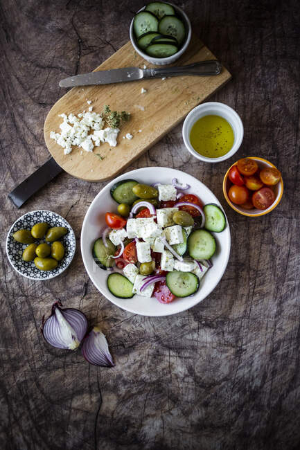 Bowl of ready-to-eat Greek salad and its ingredients — Stock Photo