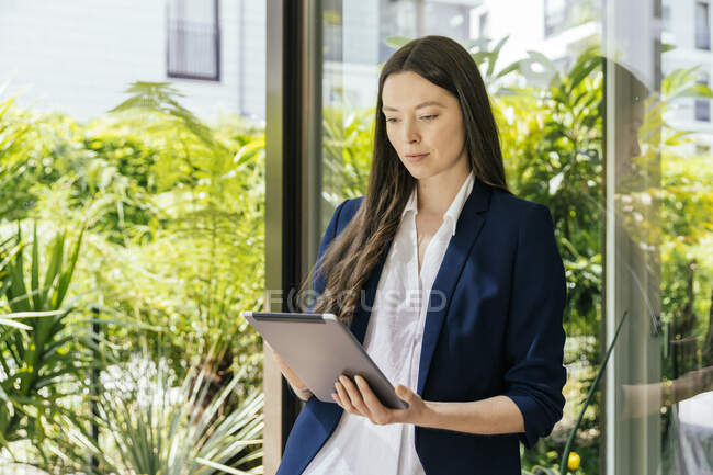 Businesswoman using tablet at glass pane — Stock Photo