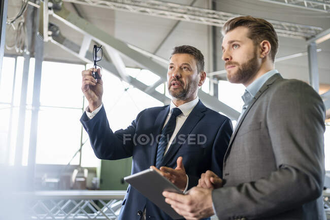Dos hombres de negocios teniendo una reunión en una fábrica - foto de stock