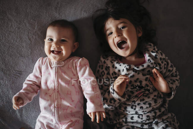 Allegro carino sorelle urlando mentre sdraiato sul letto a casa — Foto stock