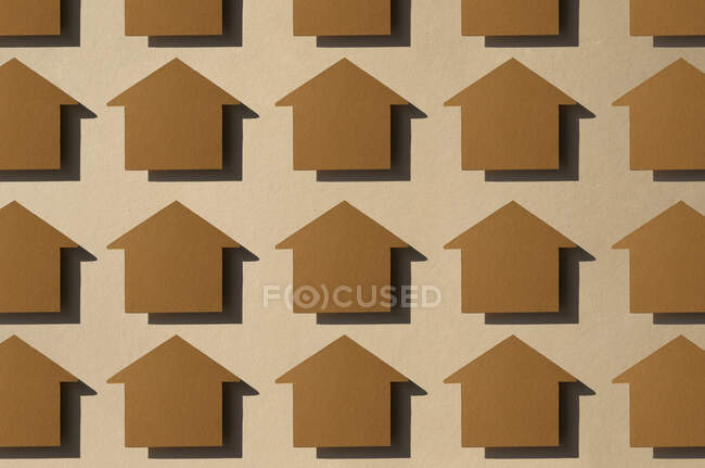 Patrón de filas de cortes de papel en forma de casa contra fondo marrón - foto de stock
