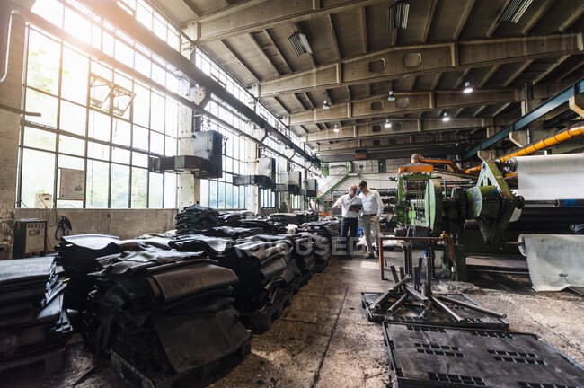 Due uomini d'affari in riunione in una fabbrica di lavorazione della gomma — Foto stock