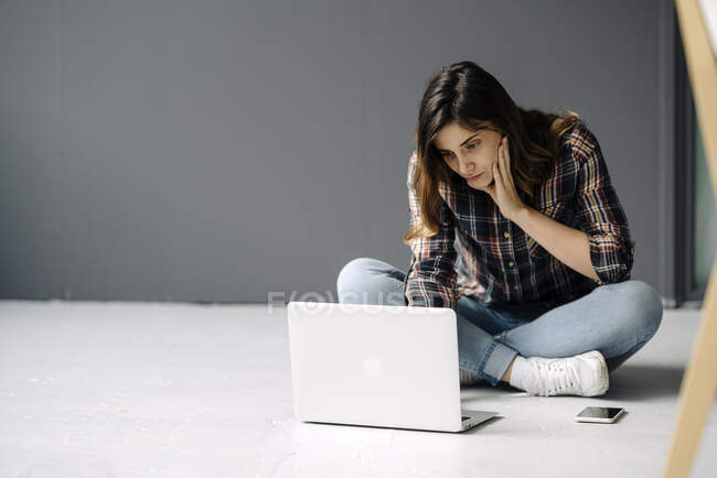 Junge Freiberuflerin sitzt mit Laptop auf dem Boden — Stockfoto