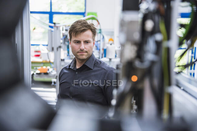 Hombre mirando una máquina en la fábrica - foto de stock