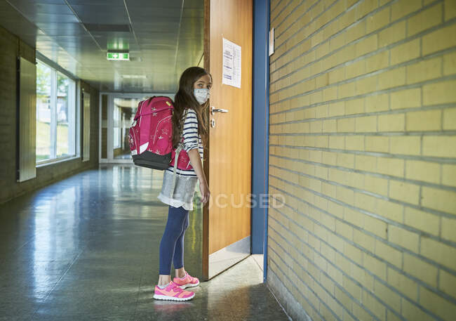 Дівчинка в масці у двері класу. — стокове фото