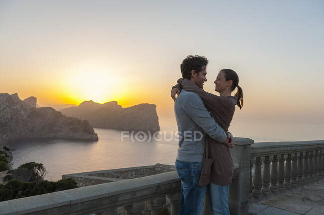 Couple standing on terrace by sunset hugging each other, Cap Formentor, Mallorca, Spain — Stock Photo