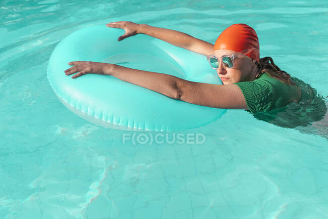 Ritratto di donna con cuffia da bagno rossa, pullover in maglia verde e occhiali da sole specchiati in piscina — Foto stock