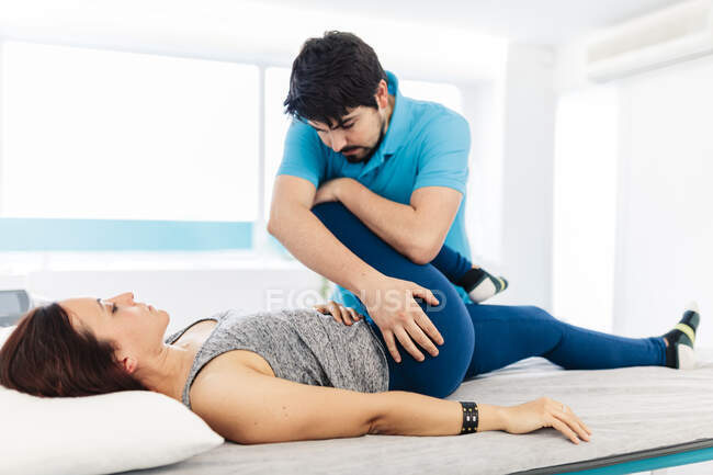 Male visually impaired physical therapist treating woman's leg in clinic — Stock Photo