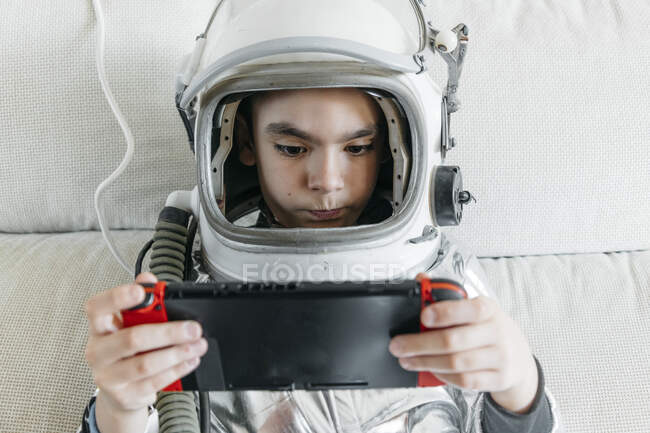 Niño jugando videojuego en una consola de juegos, con sombrero espacial - foto de stock