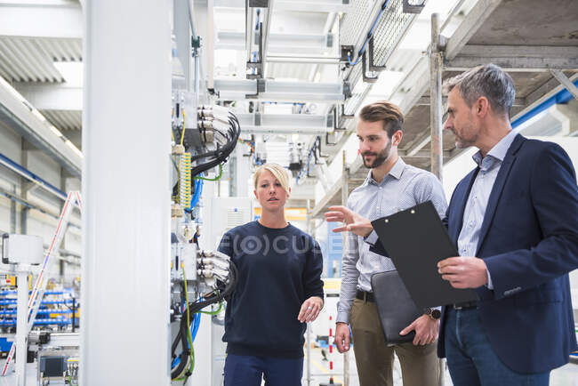Zwei Männer und eine Frau unterhalten sich in einer Fabrik — Stockfoto