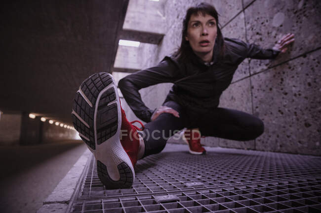 Жінка-спортсменка розігрівається перед бігом у пішохідному проході — стокове фото