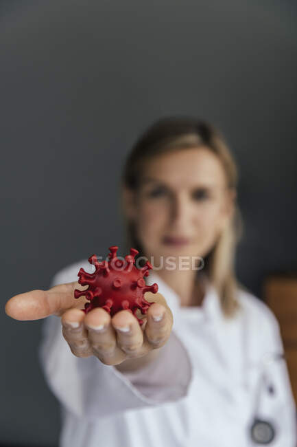 Рука ученого-женщины держит 3D модель вируса SARS-CoV-2, крупным планом — стоковое фото