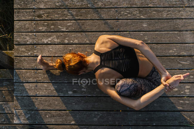 Junge Athletin streckt Körper im Sitzen auf Pier — Stockfoto