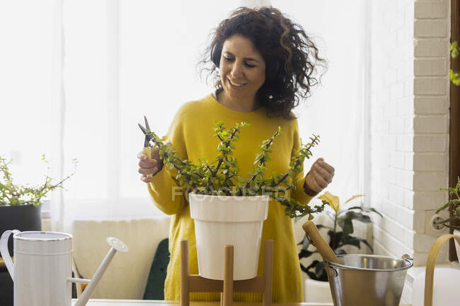 Donna a casa con cuffie e piante da potatura — Foto stock
