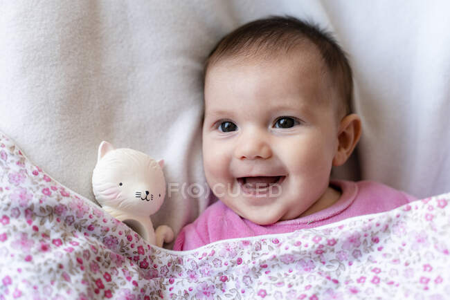 Portrait de bébé fille heureuse couchée sur le lit avec une attache — Photo de stock