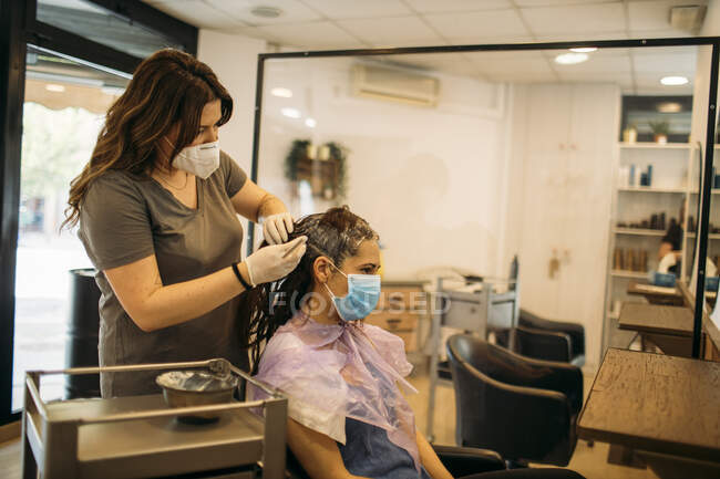 Самка перукаря з масками фарбування волосся жіночого клієнта з маскою — стокове фото