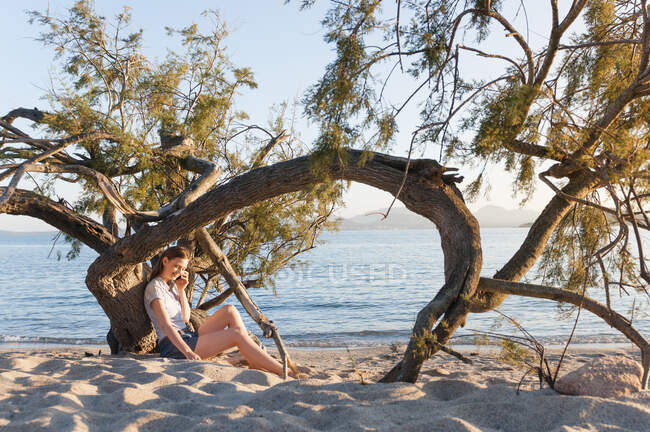 Mulher ao telefone relaxante na praia ao anoitecer, Sardenha, Itália — Fotografia de Stock