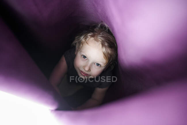 Cute girl hiding in curtain at home — Stock Photo
