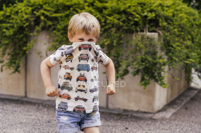 Porträt eines Jungen, der Mund und Nase mit T-Shirt bedeckt — Stockfoto